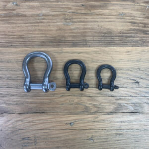 Three Bow shackles. 8mm metal on left. 6mm black centre. 5mm black right. wooden background.