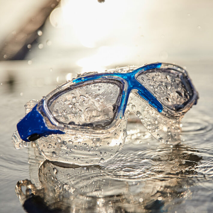 Clear swimming goggles with blue accents around the nose section. Action shot