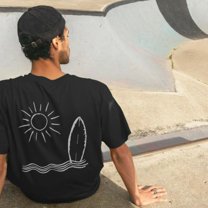 A rear view of the Reverse Happy Sea Club Tee in black as worn by a model